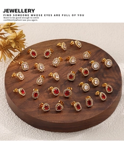 Detailed display of ruby and zircon earrings in various geometric cuts on a wooden tray