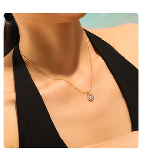 Close-up of 18K gold plated necklace with sparkling round zircon pendant on a model neck