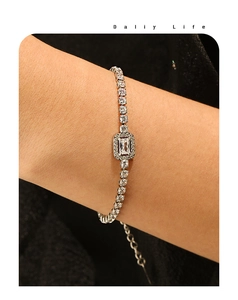 Macro shot of silver tennis bracelet featuring emerald cut center stone and adjustable chain