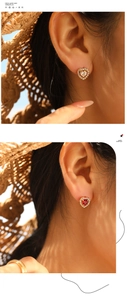 Close-up of heart-shaped gold studs with red and white gems and crystal pavé on ears