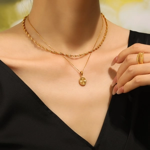 Gold layered necklace with oval sunburst pendant and textured ring on model