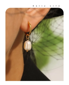 Détail des boucles d'oreilles dorées torsadées de style français avec perle d'eau douce