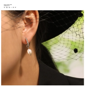 Détail macro de boucles d'oreilles torsadées avec perles d'eau douce sur modèle