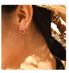 Detail of vintage style gold stud earring with red ruby and white halo diamonds on ear