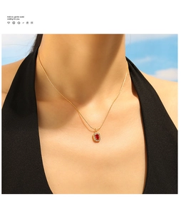 Detail of 18K gold plated necklace with a rectangular red gemstone pendant on a model