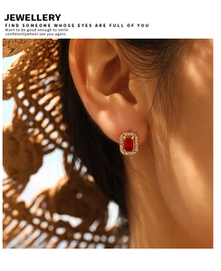 Macro shot of gold vintage earrings with ruby center stone and zircon halo on ear