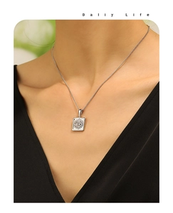 Detailed close-up of a silver eye square pendant necklace worn by a fashion model