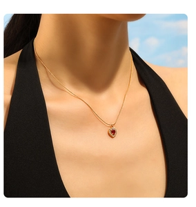 Detailed view of an 18K gold-plated heart pendant necklace with red stone on a model