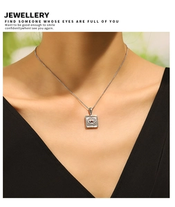 Detail view of eye pendant necklace with red gemstone on model in outdoor setting