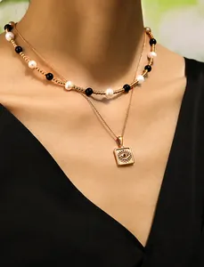 Macro detail of double-layer necklace featuring evil eye pendant with red zircon and pearls