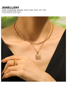 Detail of PVD gold layered necklace with evil eye square pendant and wavy textured ring