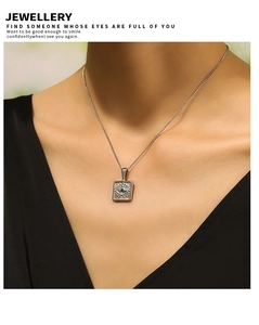 Detailed view of square evil eye pendant necklace with green gemstone on model