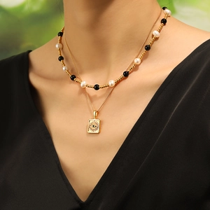 Double-layered evil eye pendant necklace with pearls and gold beads on a woman