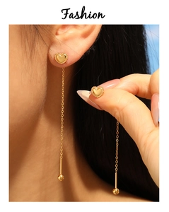 Detailed close-up of golden heart-shaped drop earrings with delicate chain tassels and beads