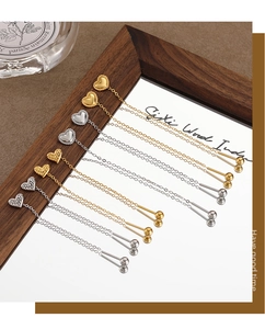Detail view of heart tassel ear threads in gold and silver finishes on a mirror surface