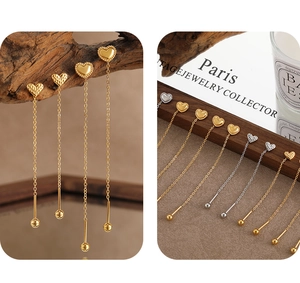 Detail showing heart-shaped tassel earrings with hammered texture and long metal chain