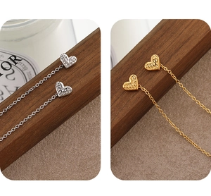 Macro detail of gold and silver heart-shaped ear wires with textured hammered finish surface