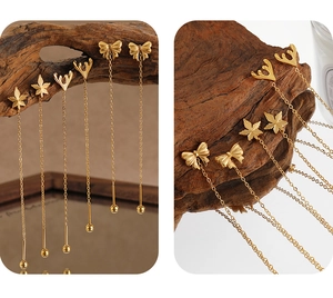 Detailed view of gold plated butterfly, maple leaf, and antler threader earrings on wood