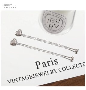 Detail of silver heart-shaped stud earrings with double layered long tassel chains