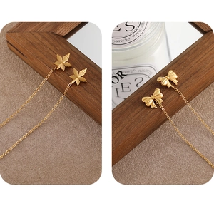 Close-up of gold bow and leaf threader earrings with fine textured metallic finish