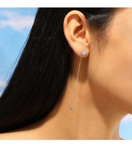 Detail of silver heart tassel earrings with pearls on long chain worn by model
