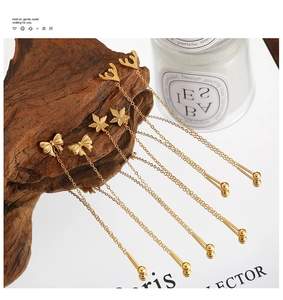 Macro detail of three gold chain earrings with bow and floral charms on a wooden base