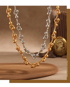 Detailed macro view of PVD gold and silver wave chain necklaces with delicate beads