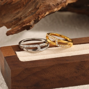 Überkreuzte X-Ringe mit Zirkonia-Mikropavé in Gold und Silber auf Holz-Schmuckdisplay
