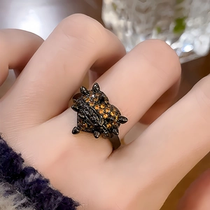 Gros plan d'une bague cœur punk plaquée noire sertie de pierres orange au doigt