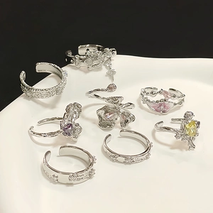 Silbernes Ring-Set mit bunten Zirkonia, Schmetterlings- und Blumendesigns auf weißem Tablett