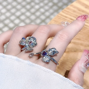 Nahaufnahme von silbernen Blumenringen mit lila Zirkonia an der Hand des Models