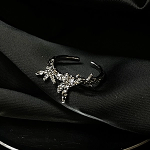 Macro shot of thorn-style adjustable metal ring with rhinestones on black satin