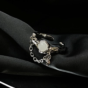 Detail of vintage gothic moonstone ring with chain on black silk fabric