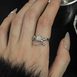 Detail of moonstone ring with twisted silver band and delicate chain on finger