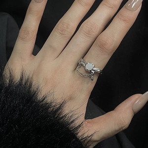Detail of silver moonstone ring with liquid metal texture and delicate chain accent