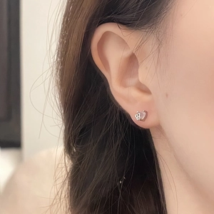 Sparkling pink heart stud earring with delicate metal butterfly detail on model ear