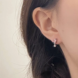 Close-up of pink heart-shaped crystal earring worn on ear with sparkling silver details