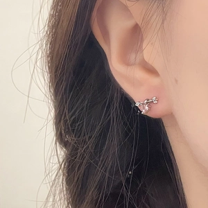 Detail of Cupid arrow earring with heart-shaped zircon worn on a woman's ear