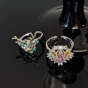 Dettaglio macro dell'anello a corna con pietra verde e anello floreale con zircone rosa