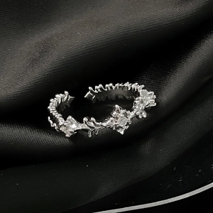 Detail eines silbernen Dornenrings mit Zirkoniasteinen auf schwarzem Satinstoff