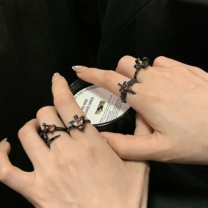 Ensemble de bagues gothiques noires avec zircon cœur rouge porté sur une main