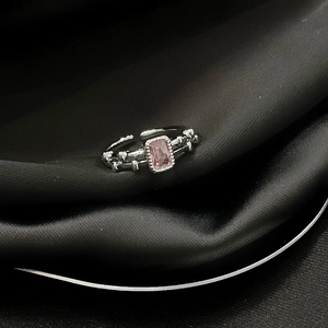 Detailaufnahme des rosa rechteckigen Edelsteinrings auf elegantem schwarzem Seidenstoff