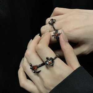 Détail d'une bague gothique noire avec croix et pierre de zircon rouge en forme de cœur