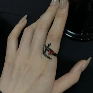 Détail d'une bague gothique dague noire perçant un cœur en zircon rouge, anneau ouvert