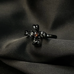 Détail d'une bague gothique en métal noir avec zircon rouge sur tissu de soie grise