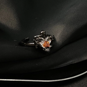 Gros plan d'une bague renard noire avec pierre orange sur fond de soie noire
