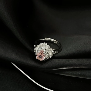 Detalle macro de anillo de lujo con circón rosa ovalado y micro-pavé sobre seda negra
