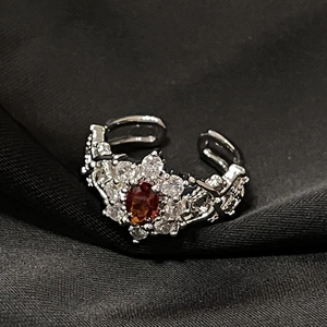 Macro de anillo de plata con piedra de circón rojo ovalada y detalles florales blancos