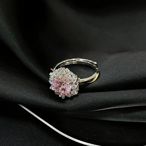 Detalle macro de anillo plateado ajustable con gema rosa sobre elegante seda negra