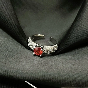 Detalle de circón rojo en anillo de aleación negra con textura de celosía de diamante